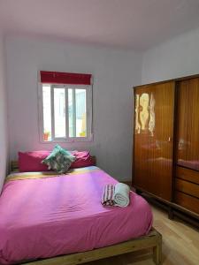 a bedroom with a large bed with pink sheets and a window at aparment puerto Alto in Madrid