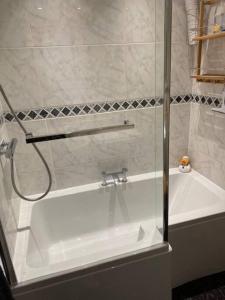 a shower with a glass door next to a white bath tub at The Bolt Hole, Cotswold Cottage, Moreton-In-Marsh in Moreton in Marsh