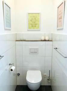 une salle de bain avec toilettes et un tableau au mur dans l'établissement FERIENWOHNUNG SEEBRISE mit sonniger Dachterrasse, à Uhldingen-Mühlhofen 4 autres photos