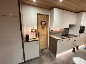 a kitchen with white cabinets and a sink and a door at TIGNES VAL CLARET A LA CONQUETE DES SOMMETS MOUTIERE B23 in Tignes