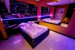 2 camas en una habitación con luces moradas en Motel I Love Pelotas, en Pelotas