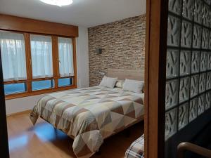 a bedroom with a bed and a brick wall at Apartamento Puerta del Pirineo in Sabiñánigo