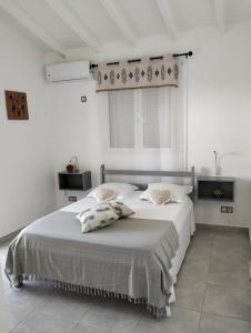 a white bedroom with a large bed with two pillows at Villa Mircene in Saint-Louis