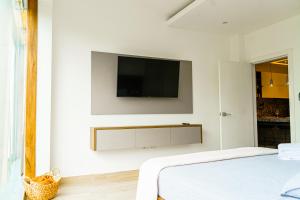 a white bedroom with a tv on the wall at Luxury Apartments estilo New York in Guayaquil