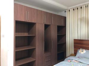 Aseda Lodge Gh في آكرا: غرفة نوم بأرفف خشبية وسرير