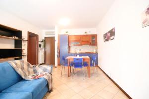 a living room with a blue couch and a kitchen at Campovolo Cozy Apartment in Reggio Emilia