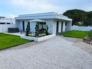 Cette maison blanche dispose d'une terrasse et d'un parasol. dans l'établissement Villa Valentin 2 chambres avec jardin à Calvi, à Calvi