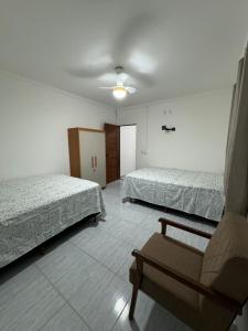 a room with two beds and a chair in it at Residencial Vilaça in Guarapari
