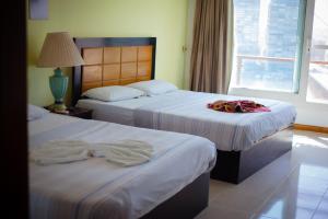 Jasmine Nile Sky Hotel في القاهرة: سريرين في غرفة الفندق عليها مناشف