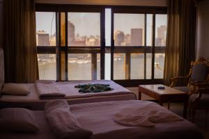 two beds in a hotel room with a large window at Jasmine Nile Sky Hotel in Cairo