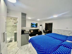 a bedroom with a blue bed and a bathroom at THE ROYAL BOUTIQUE STUDIO BY LONDON HEATHROW UK, PRIVATE APARTMENT OFFER's FREE PARKING, WIFI , KITCHEN & LAUNDRY SERVICES, SLEEP 6 in Hayes