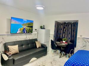 a living room with a couch and a table and a tv at THE ROYAL BOUTIQUE STUDIO BY LONDON HEATHROW UK, PRIVATE APARTMENT OFFER's FREE PARKING, WIFI , KITCHEN & LAUNDRY SERVICES, SLEEP 6 in Hayes