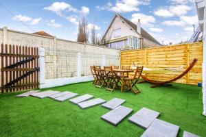a patio with a table and chairs on grass at Joyful tiny house seaside in Cabourg
