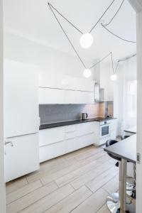 a white kitchen with white cabinets and a table at Waterfront District Apartment in Genova