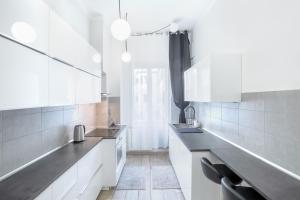 una cocina con armarios blancos y encimeras negras en Waterfront District Apartment, en Génova