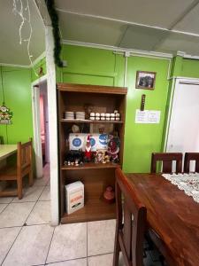 um quarto com paredes verdes, uma mesa e uma prateleira em HOSPEDAJE BETTY em Punta Arenas