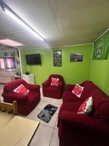uma sala de estar com sofás vermelhos e paredes verdes em HOSPEDAJE BETTY em Punta Arenas