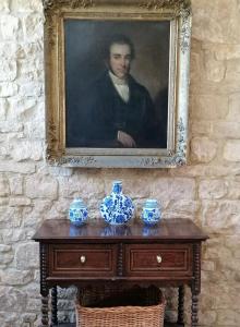 Ein Bild eines Mannes auf einem Tisch mit Vasen drauf. in der Unterkunft Merriman Cottage in Chipping Campden