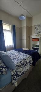 a bedroom with a bed with a blue comforter and a window at Character 2-Bedroom Unit in Masterton