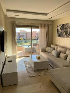 een woonkamer met een bank en een groot raam bij Beautiful apartment in Golf City Marrakech in Marrakesh