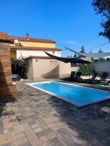 a swimming pool with a patio umbrella and chairs at Kuća za odmor L&L in Bibinje