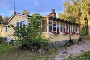 una casa amarilla con flores a un lado. en Trevligt hus/stuga i Svärtinge, en Norrköping