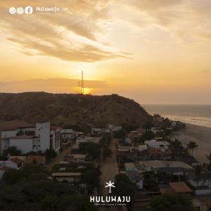 uma vista para uma cidade com o pôr-do-sol sobre o oceano em Huluwaju Hotel em La Bocana