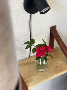 a vase with red flowers sitting on a wooden shelf at Las Quimeras in Nono