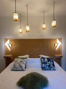 a bedroom with a large bed with pillows and lights at Le Chatel en Beaujolais in Valsonne
