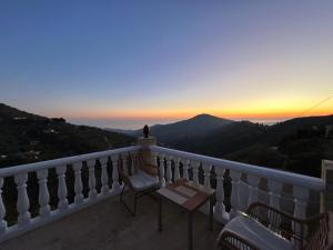 een balkon met een tafel en stoelen bij zonsondergang bij Villa Víctor in Cómpeta