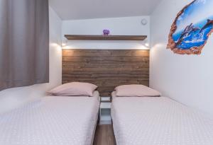 2 Betten in einem kleinen Zimmer mit weißen Wänden in der Unterkunft Mobile Home SIMBA in Biograd na Moru