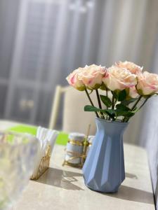een blauwe vaas gevuld met roze rozen op een tafel bij Elizavetta in Bisjkek