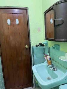 ein Badezimmer mit einem Waschbecken und einer Holztür in der Unterkunft Villa Paquita - Arco de Bellavista in Riobamba