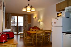 a kitchen and dining room with a table and a refrigerator at Appartement 6 places aux pieds des pistes avec piscine, wifi et parking privé PMR in Orcières