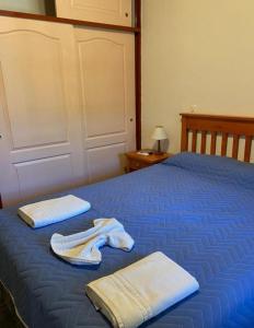 Una cama azul con toallas encima. en Le Marche Apart Hotel en Merlo
