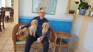 a man sitting in a chair with three dogs at Hotel Baia Cea in Bari Sardo