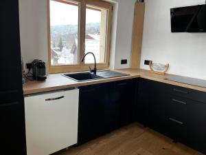 eine Küche mit schwarzen Schränken, einem Waschbecken und einem Fenster in der Unterkunft Le Chappart in Les Carroz d'Araches