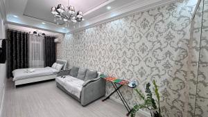 een woonkamer met een bank en een bed bij Elizavetta in Bisjkek