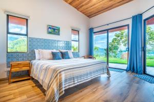 a bedroom with a bed in a room with windows at Villa Roca Ocean to Mountain Views - by Pura Villas in Ojochal