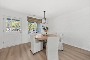 a white dining room with a wooden table and white chairs at 542 Tarpon Pond Cottage in Seabrook Island
