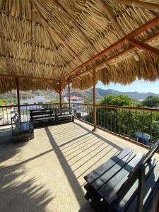 a patio with benches and a straw umbrella at Hostal Acuarius in Taganga