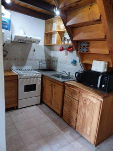 a kitchen with a stove and a sink at La Cabañita in Villa General Belgrano