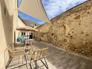 a patio with chairs and a table and a stone wall at Junglissime - By BEST KEYS - Déco Jungle & Grand Patio Privé - 1 chambre séparée & 1 canapé convertible - Centre Ville - Smart TV - Machine à Café Nespresso - WiFi Fibre - Check-in Autonome - Parking Facile & Gratuit in Sens