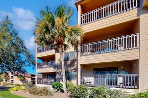 a tall building with a palm tree in front of it at HH Beach & Tennis F11 in Hilton Head Island