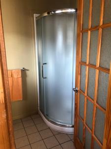 een douche in een badkamer met een glazen deur bij Le chalet du Golf à Rimouski in Rimouski