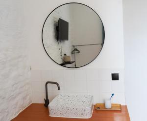 ein Bad mit einem Waschbecken und einem Wandspiegel in der Unterkunft Le P'tit Bijou - Centre de Liège in Lüttich