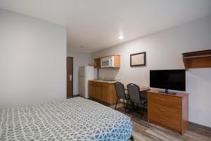 a bedroom with a bed and a desk with a television at WoodSpring Suites Greenville Simpsonville in Simpsonville
