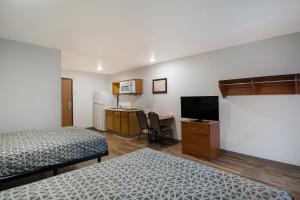 a room with two beds and a kitchen with a television at WoodSpring Suites Greenville Simpsonville in Simpsonville