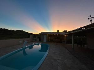 una piscina frente a una casa con puesta de sol en Recanto Vó Rosa, en Socorro