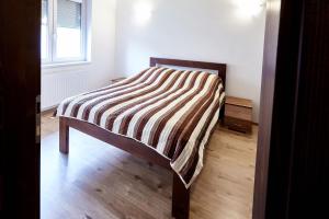 NyékládházaにあるDeák Apartmanのストライプ毛布が付いた部屋のベッド1台